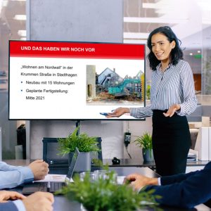 Frau neben Bildschirm mit Unternehmenspräsentation